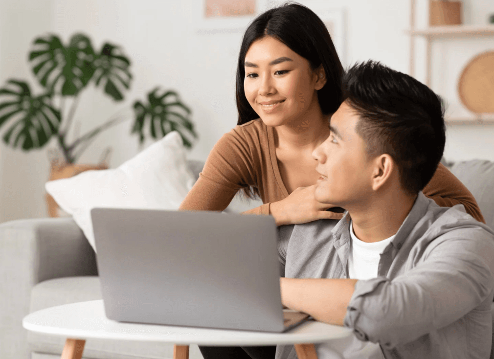 Happy couple working together on laptop in modern home